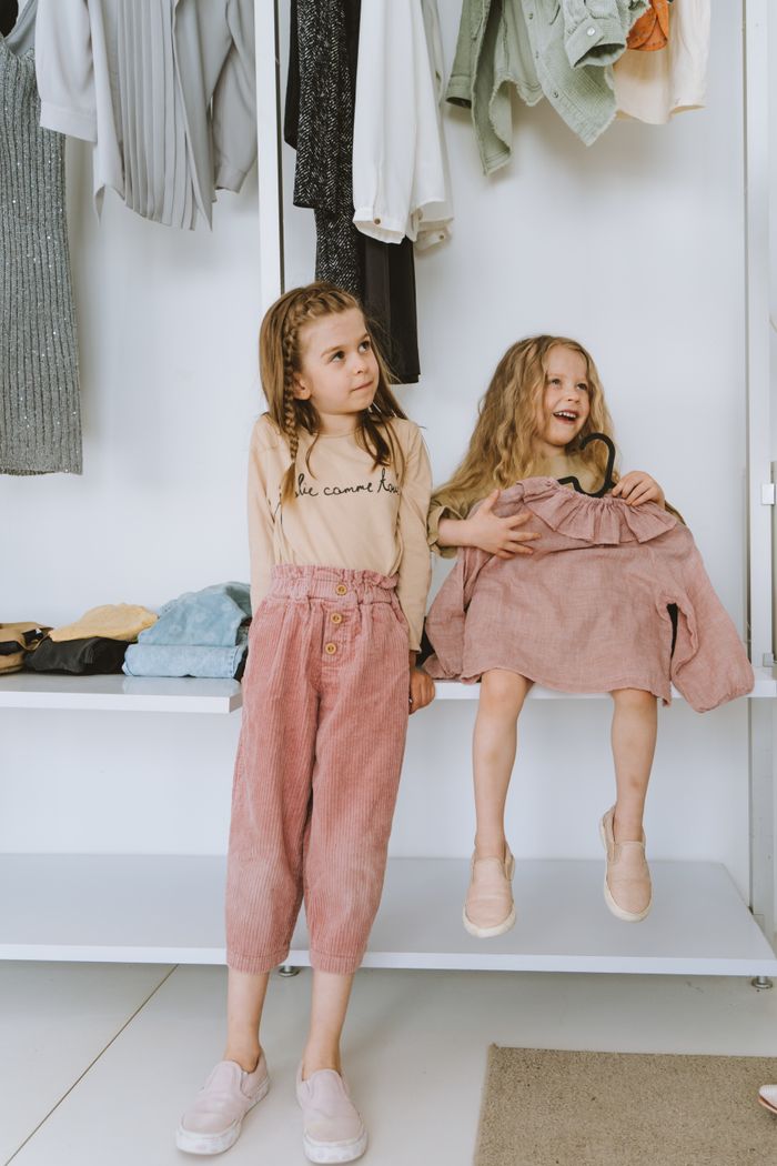 Crafting Captivating Headlines: Your awesome post title goes here Two smiling sisters enjoying a cozy moment together in a wardrobe setting, radiating joy and warmth.