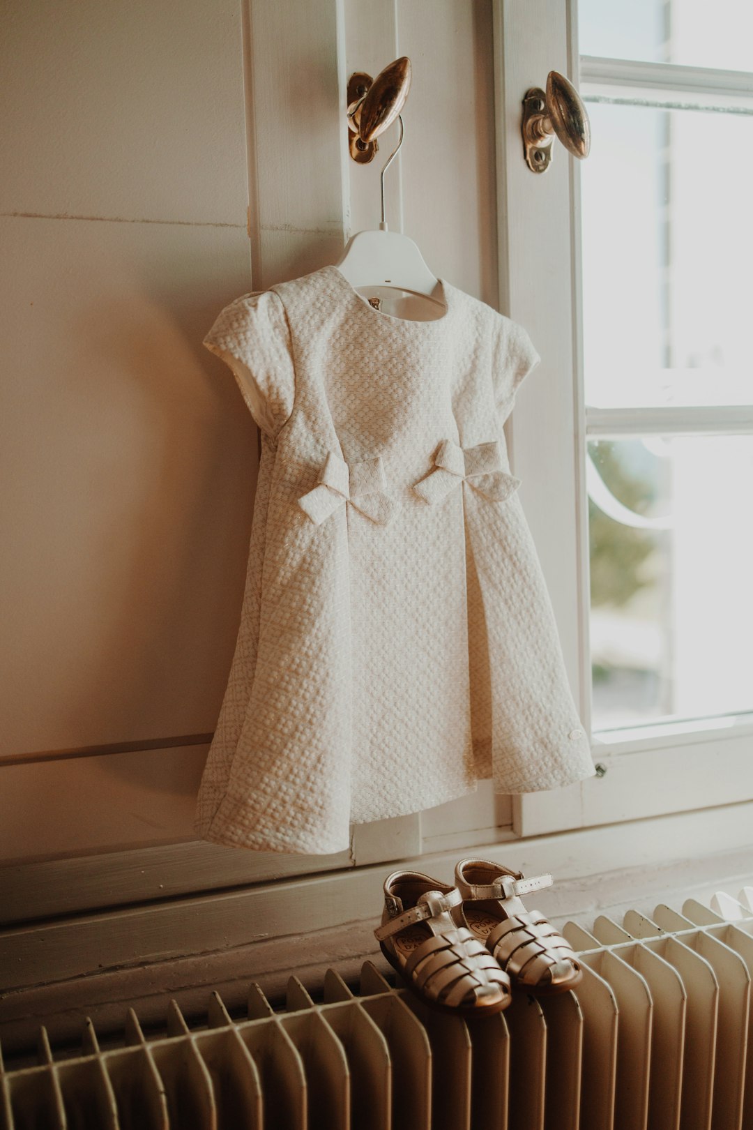 a-white-dress-hanging-on-a-radiator-next-to-a-pair-of-shoes-jh6nzse9o6e