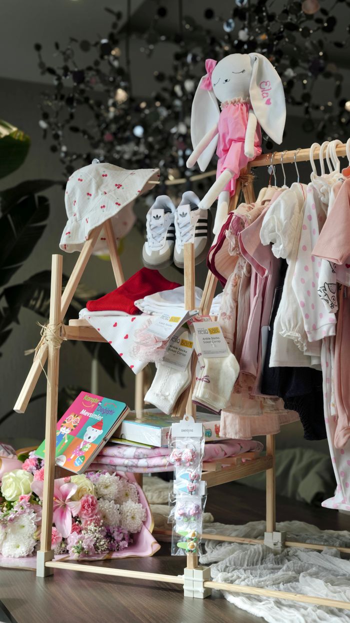 Adorable baby clothing set with plush toys and styled floral decor, perfect for newborn gifts.